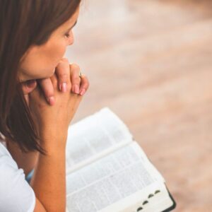 The woman prays after reading a Bible verse.