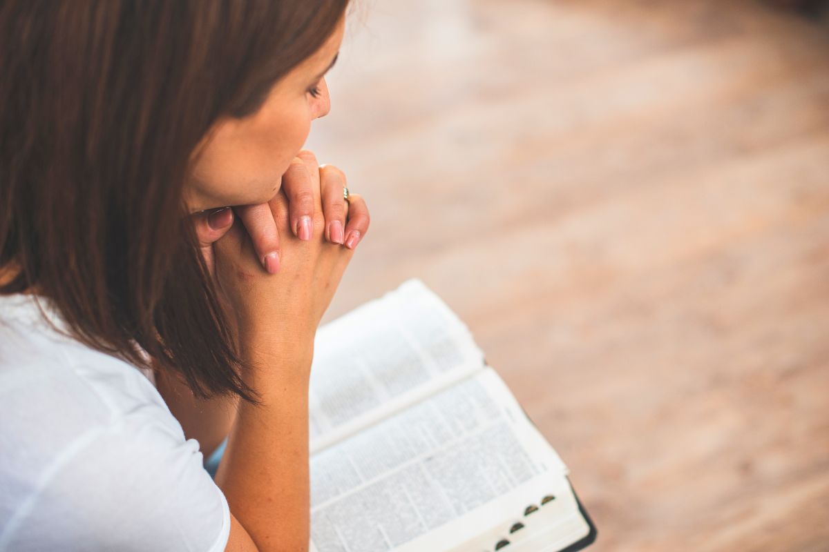 The woman prays after reading a Bible verse.