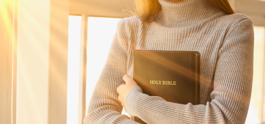 Woman holding a Holy Bible close, inspired by bible verses about being a woman of god.