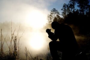 A man is praying devoutly on his knees.