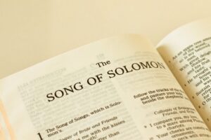 Open Bible with a cross resting on the page of song solomon verses.