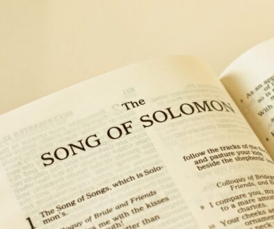 Open Bible with a cross resting on the page of song solomon verses.