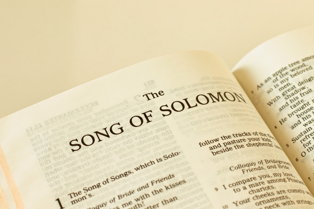 Open Bible with a cross resting on the page of song solomon verses.