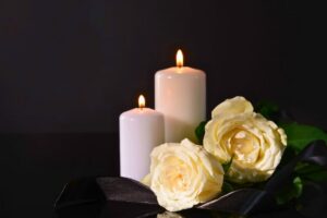 Lit candles and white roses symbolizing hope in a catholic prayer for the dead.