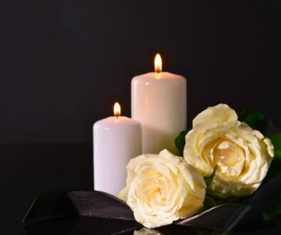 Lit candles and white roses symbolizing hope in a catholic prayer for the dead.