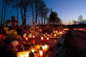 Candles lit beside graves on All Souls Day.