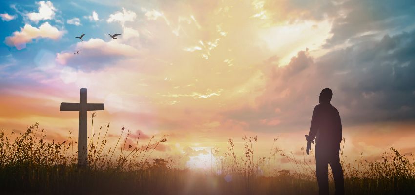 Dramatic silhouette of a man on a mountain peak at sunrise through frosted glass effect, symbolizing empowerment from a bible verse for strength.