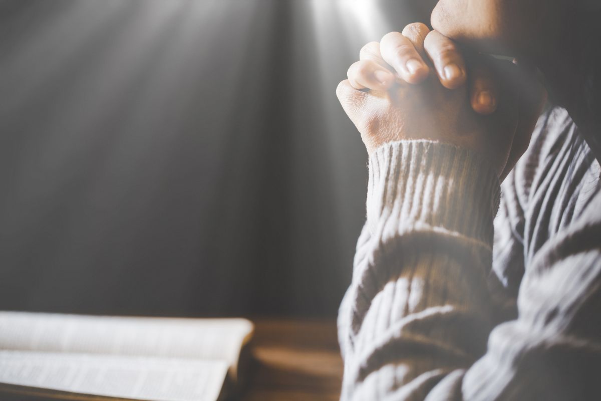 A Christian is praying in front of their bible.