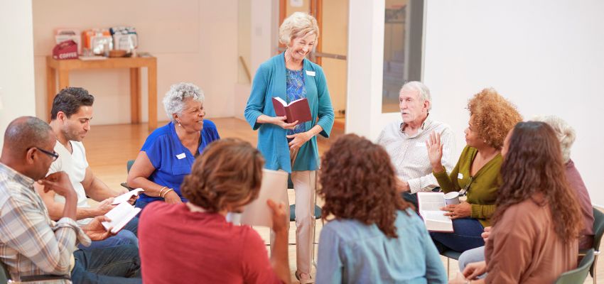 Group of adults in a circle discussing faith and life lessons based on biblical principles in a community setting.