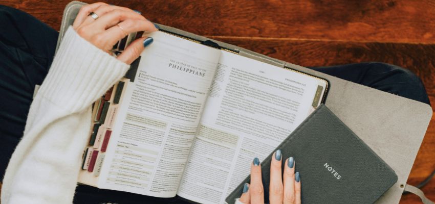 Open Bible and notebook on a table as someone studies and writes notes about biblical principles.