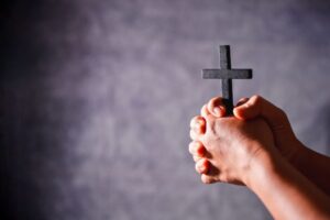 A man holds a wooden cross while praying.