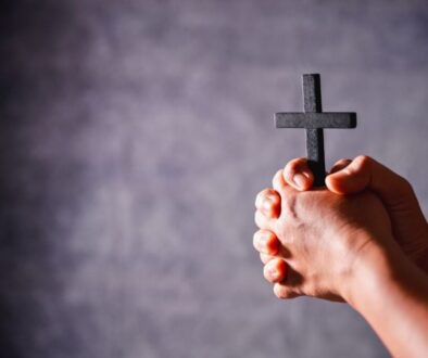 A man holds a wooden cross while praying.