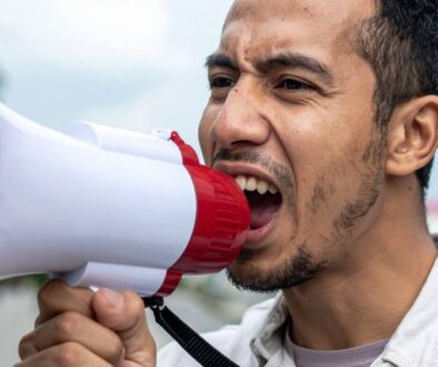 An angry protester yells into a microphone.