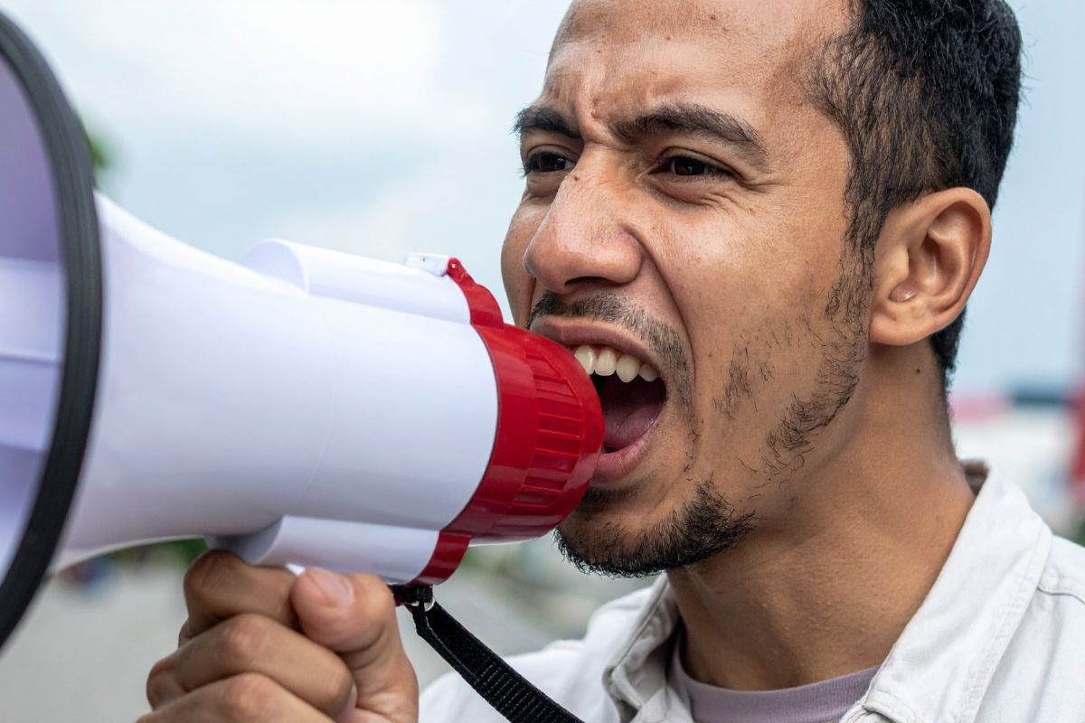 An angry protester yells into a microphone.