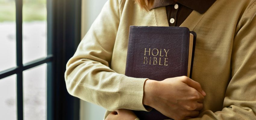 Person gently holding a Holy Bible, perfect for reading bible verses for mothers
