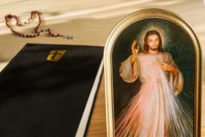The Divine Mercy image beside a bible and rosary.