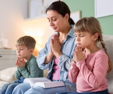 Family sharing peaceful prayers for children together on the couch with an open book.