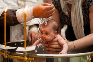 A baby being baptized by a priest.