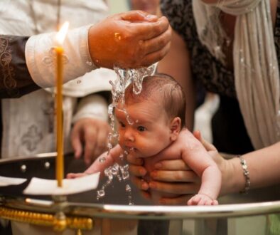 A baby being baptized by a priest.