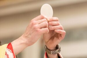 A priest holds up the Eucharist during Mass.