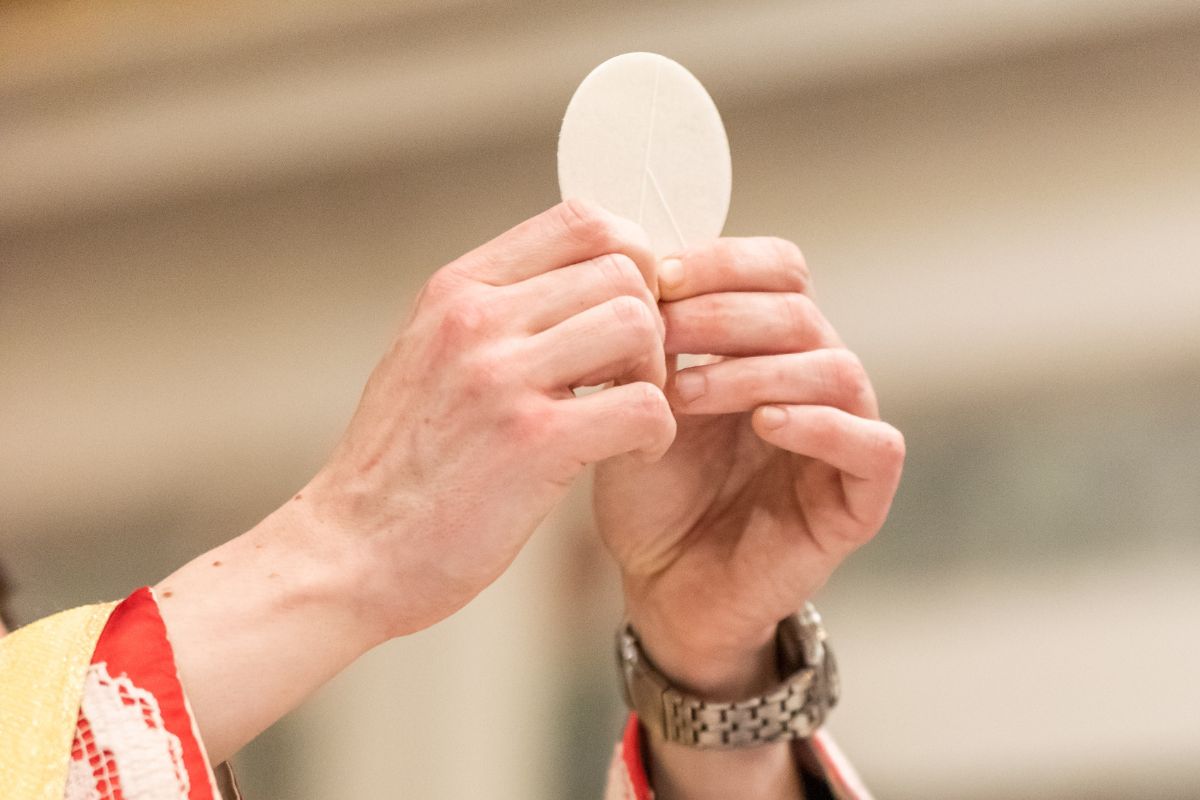 A priest holds up the Eucharist during Mass.