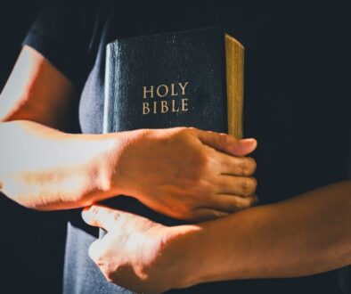 Person holding a Holy Bible close, illustrating what does the bible say about money and faith.