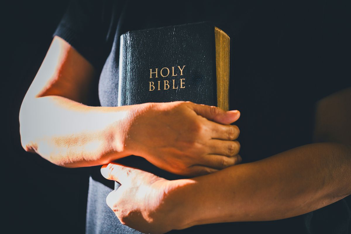 Person holding a Holy Bible close, illustrating what does the bible say about money and faith.