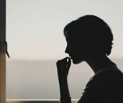 Silhouette of a woman looking out the window in a moment of discouragement, seeking comfort through bible verses for discouragement.