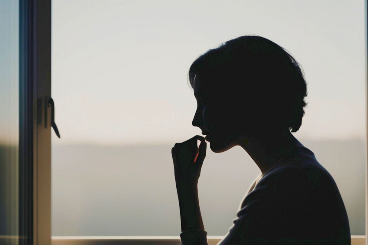Silhouette of a woman looking out the window in a moment of discouragement, seeking comfort through bible verses for discouragement.