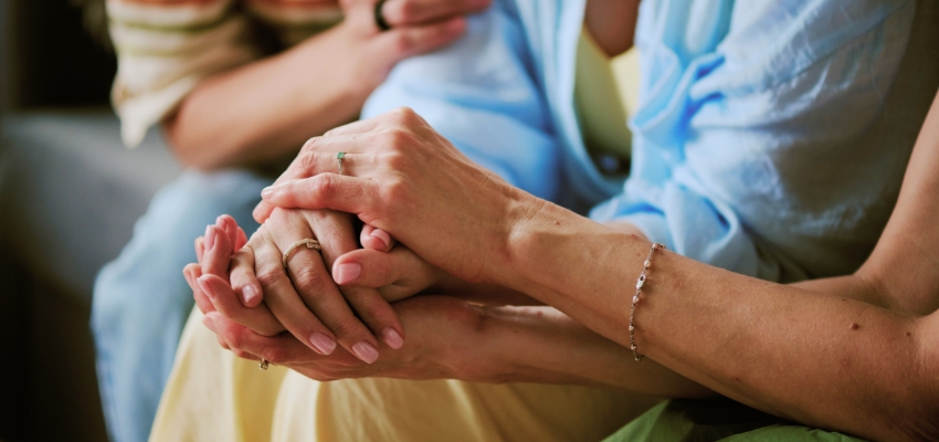Supportive hands gently holding each other during a prayer for a friend