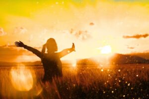 A woman experiences refreshment of her soul in a field during sunset.