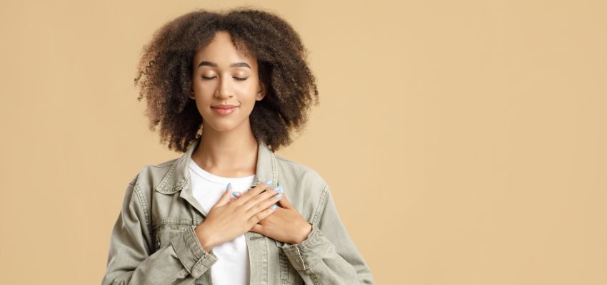 Young woman with hands over her heart expressing thankfulness inspired by bible verses about gratitude.