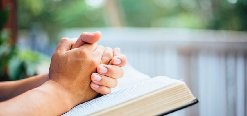 Hands resting on an open Bible in quiet reflection while considering in what order should i read the bible.