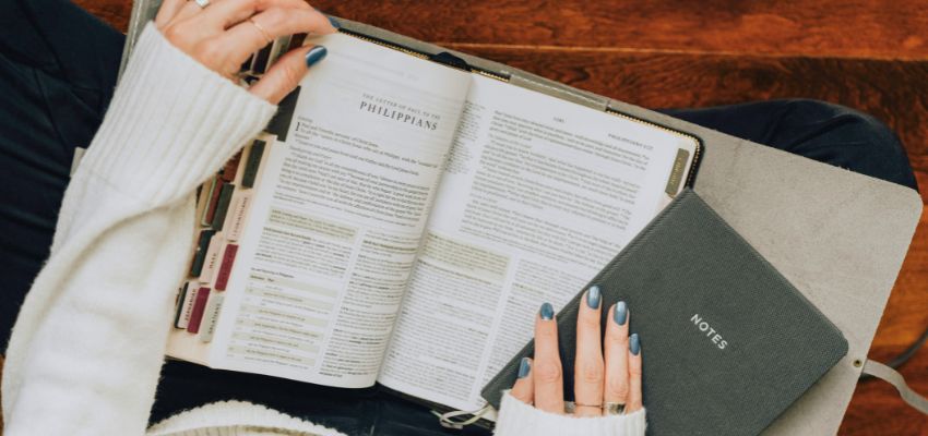 Reader studying Philippians with a notes journal, exploring in what order should i read the bible.